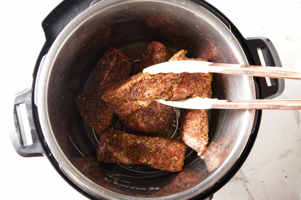 Placing country style ribs in an Instant Pot.