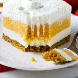 A pumpkin cheesecake bar and a fork on a plate.