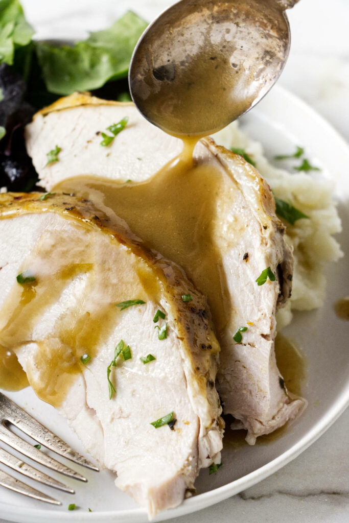 Two slices of turkey on a plate with mashed potatoes and gravy.