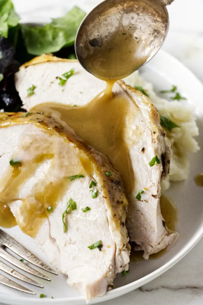 Two slices of turkey on a plate with mashed potatoes and gravy.