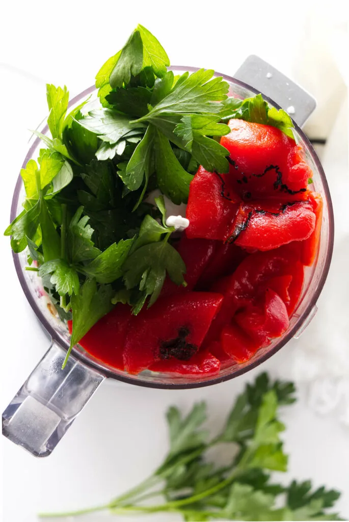 red chimichurri ingredients stuffed into a food processor