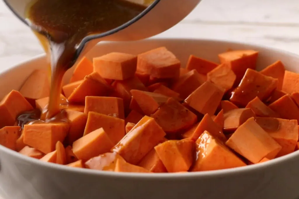 Adding the sauce to the sweet potatoes.