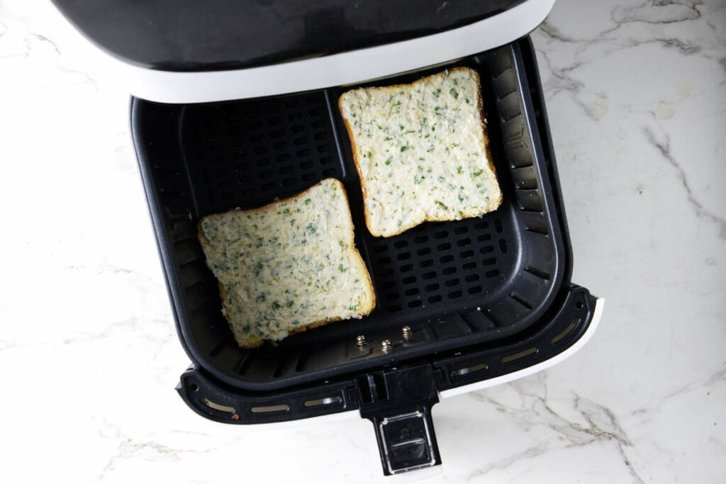Two slices of garlic bread in an air fryer.