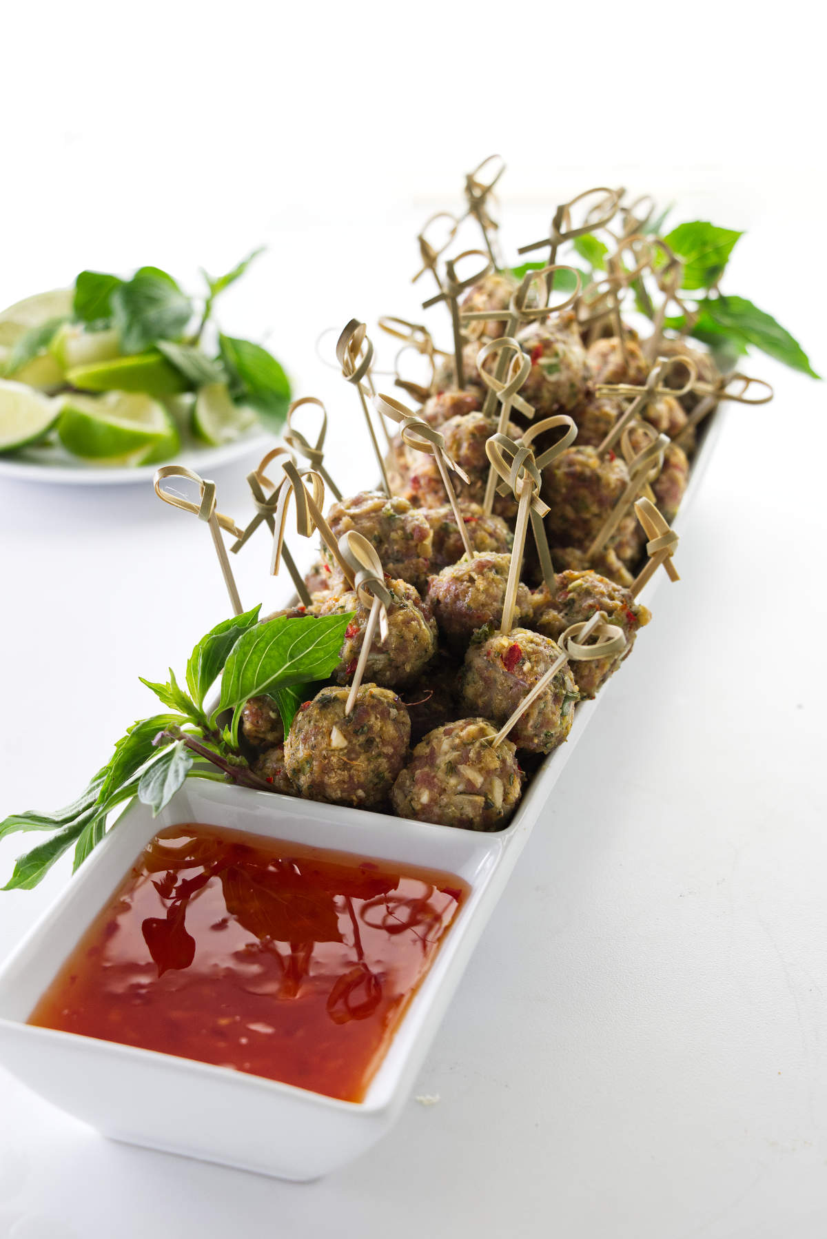 Overhead photo of appetizers in a serving dish filled with Asian Pork Meatballs and a sweet/savory chili dipping sauce.