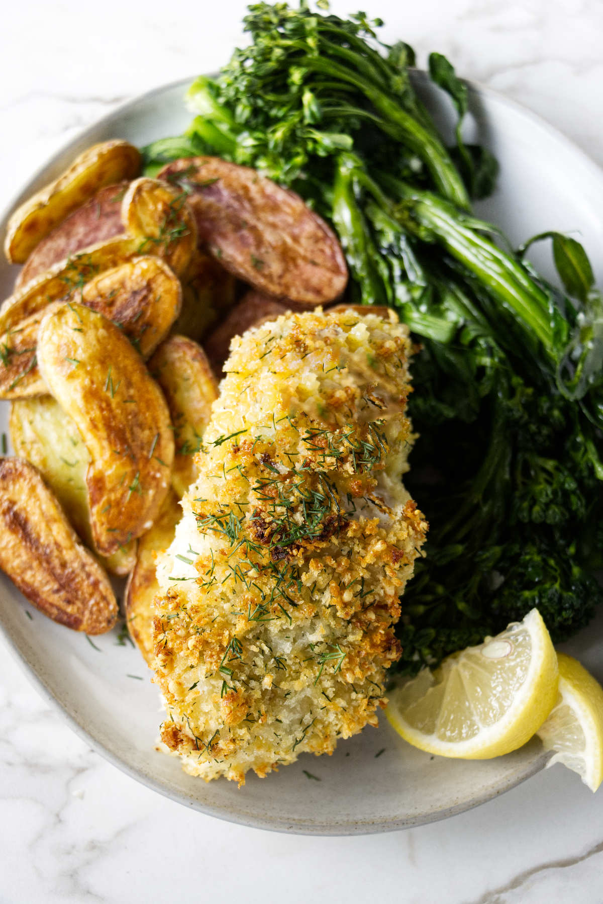 A baked haddock fillet on a plate with vegetables.