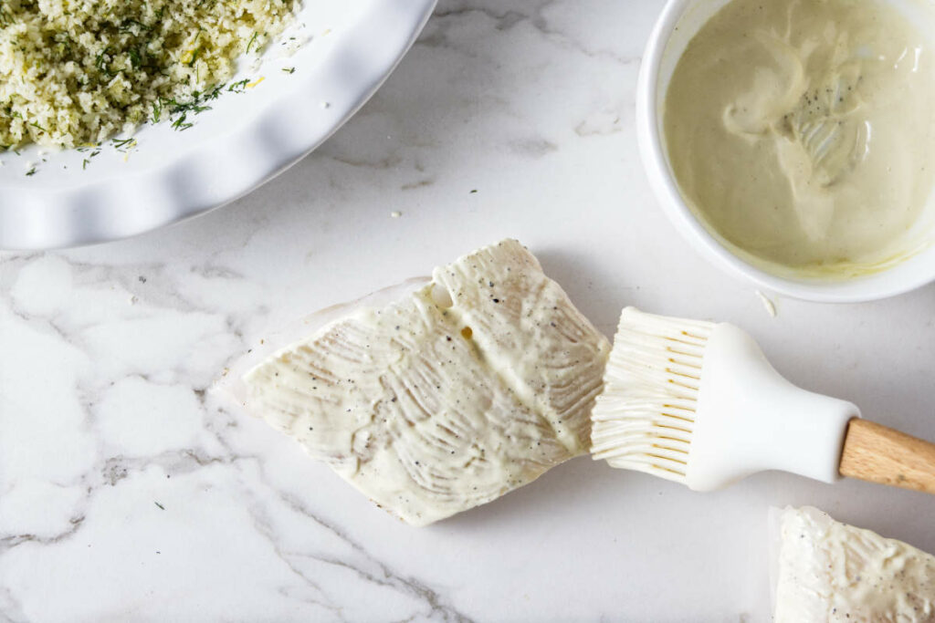 Coating haddock in a mustard mixture.