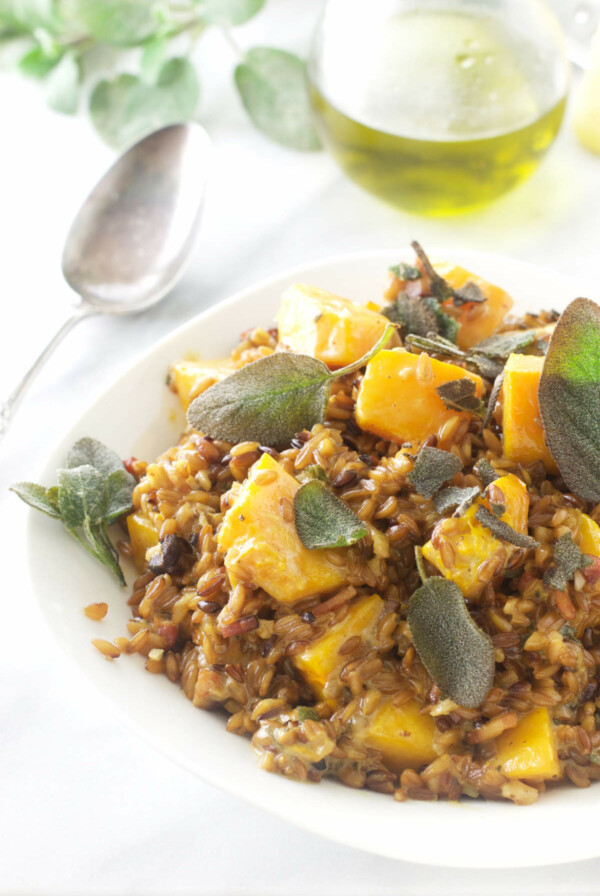 A dish of farro risotto next to a bottle of olive oil.