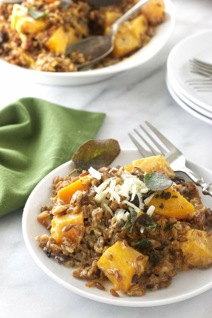 Two plates of butternut farrotto topped with shredded cheese.