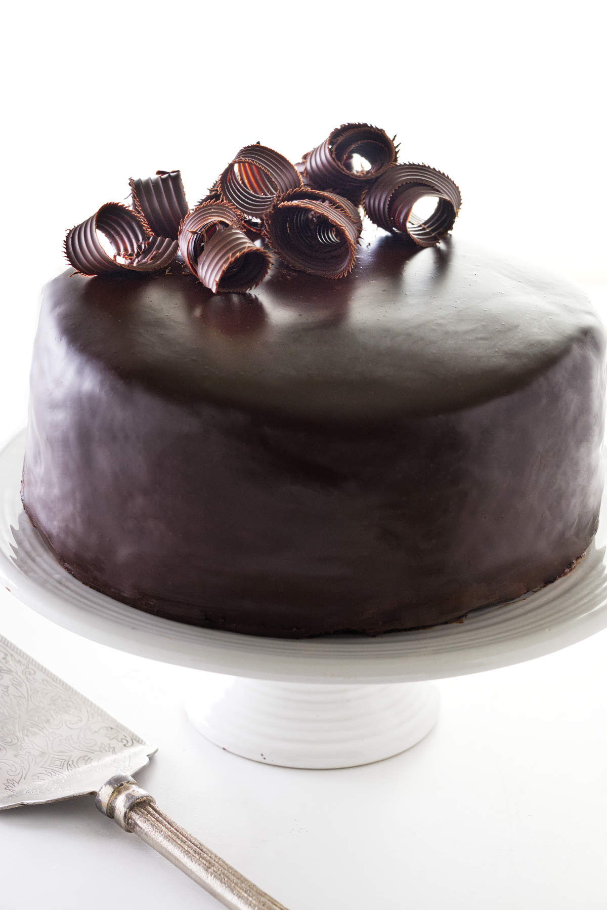 Chocolate Ganache Cake on a cake pedestal and decorated with chocolate curls.