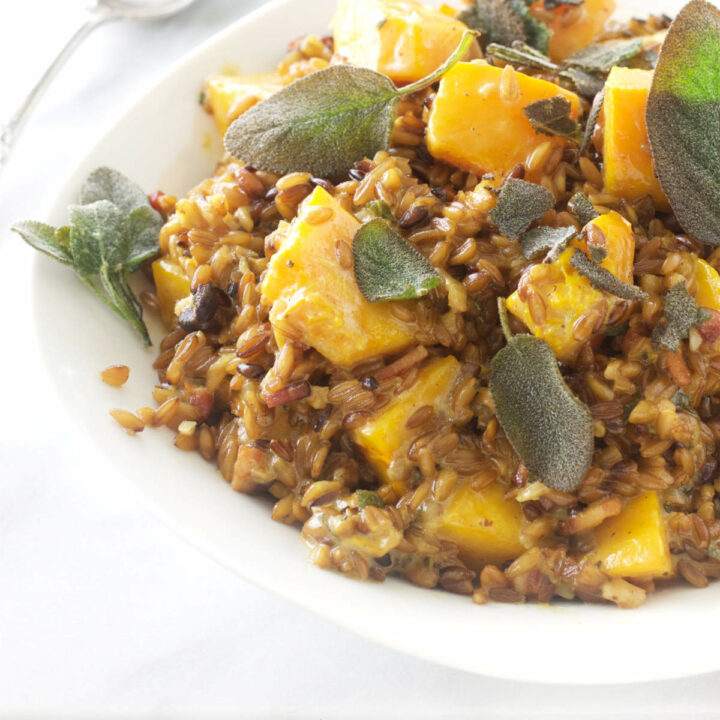 A plate filled with farro risotto with cubes of roasted butternut squash.