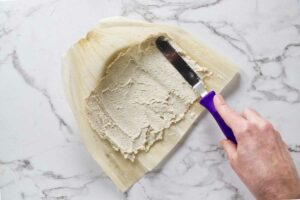 Spreading masa dough on a corn husk.