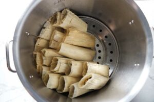 Stacking tamales in a large pot.
