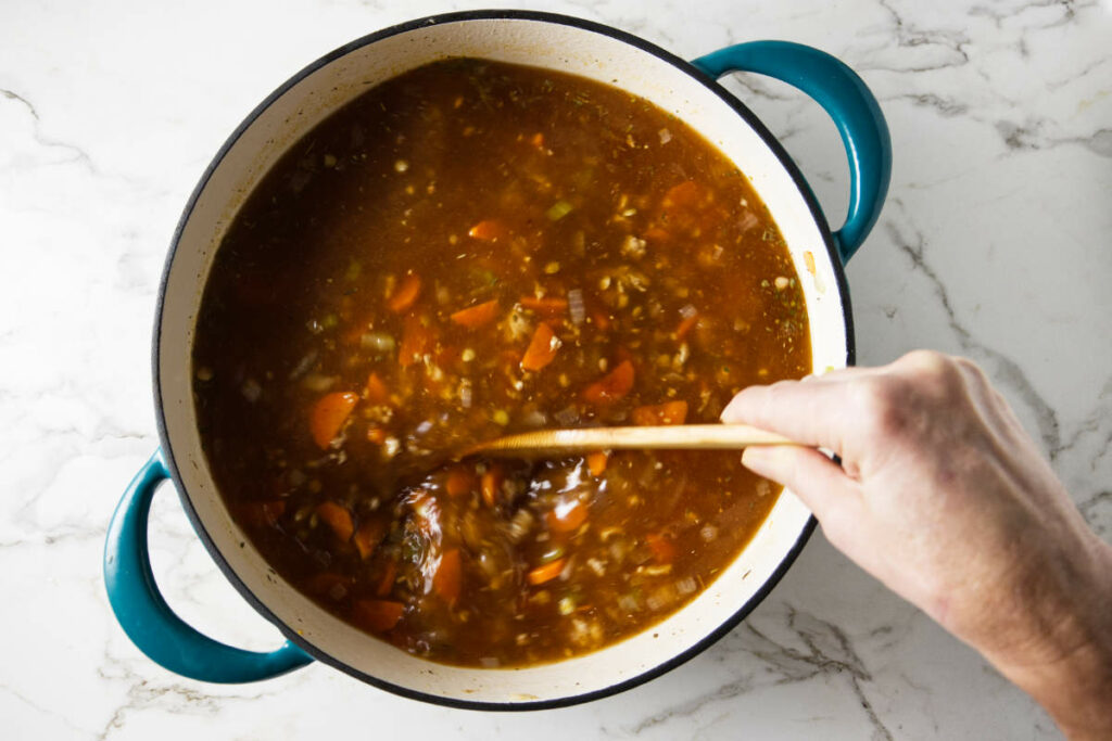 Adding lentils and broth to the pot.