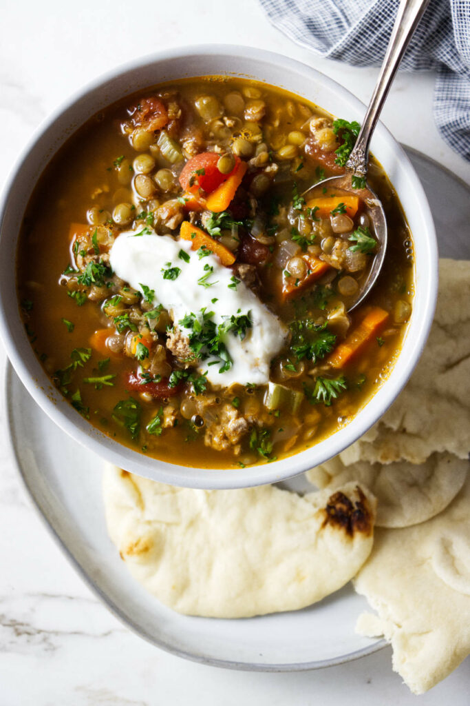 A bowl of lentil soup with a dollop of sour cream on top.