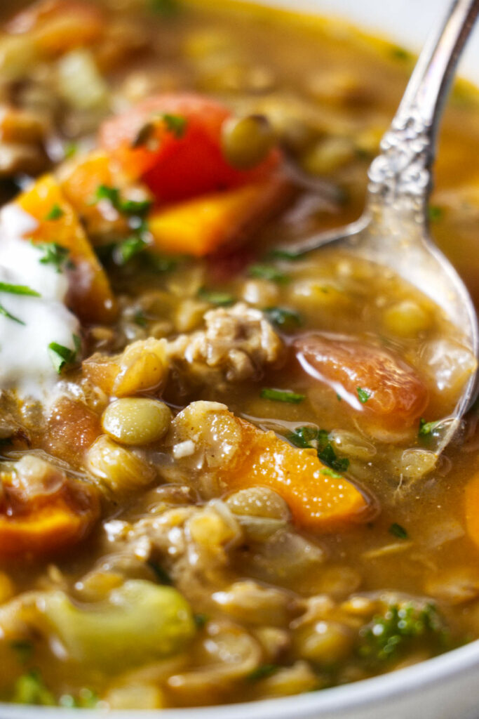 A spoon scooping some lentil turkey soup.