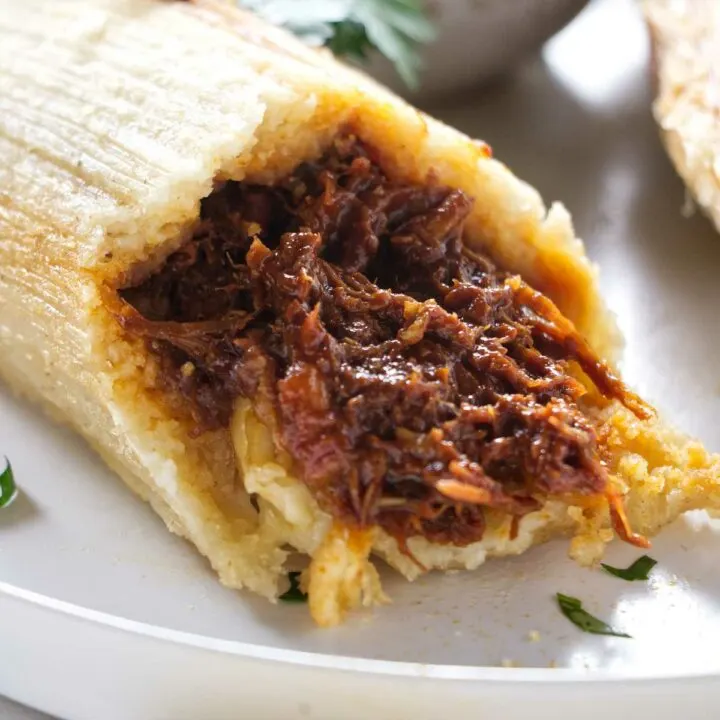 A tamale broken open to show the pork filling.
