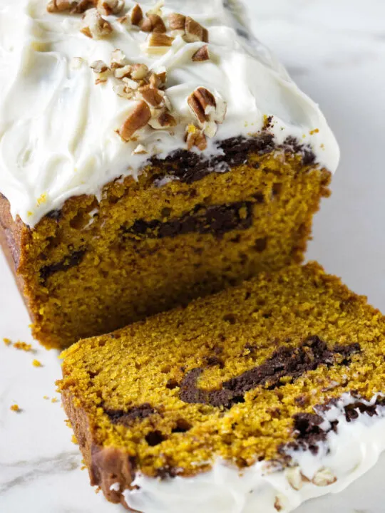 A pumpkin loaf cake with a chocolate swirl and cream cheese frosting.