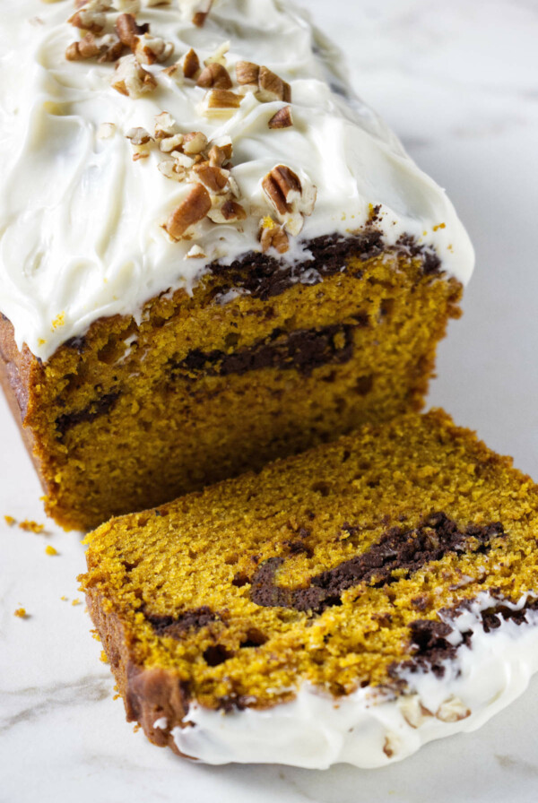 A pumpkin loaf cake with a chocolate swirl and cream cheese frosting.