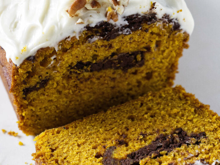 A pumpkin loaf cake with a chocolate swirl and cream cheese frosting.