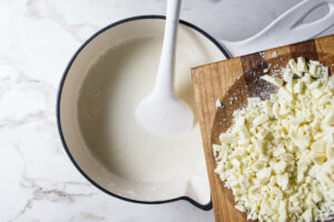 Adding white chocolate to a saucepan of hot milk.