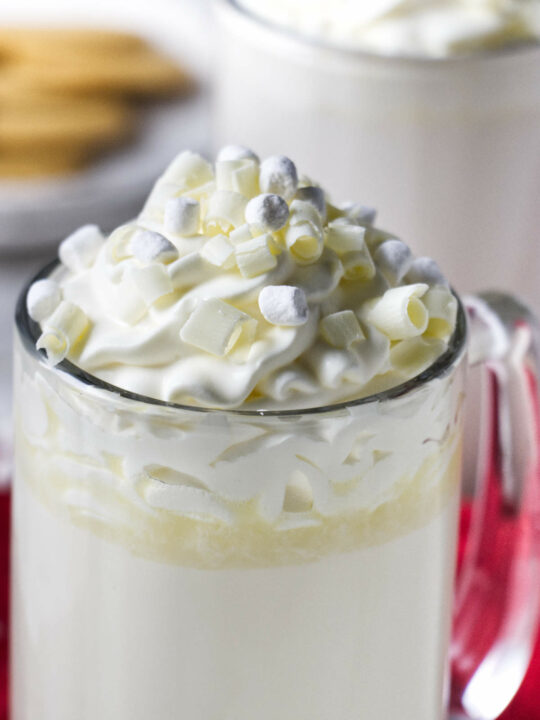 A mug of white hot chocolate with mini marshmallows and whipped cream on top.