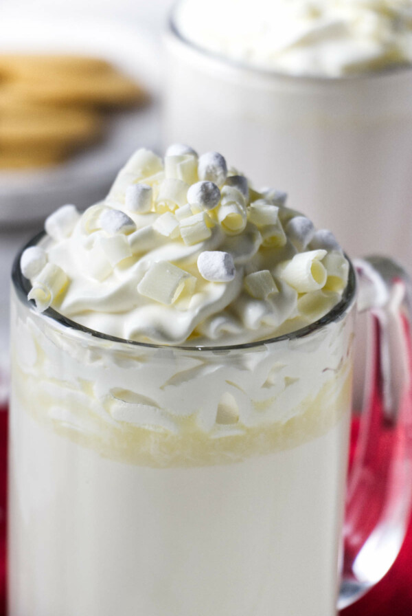 A mug of white hot chocolate with mini marshmallows and whipped cream on top.