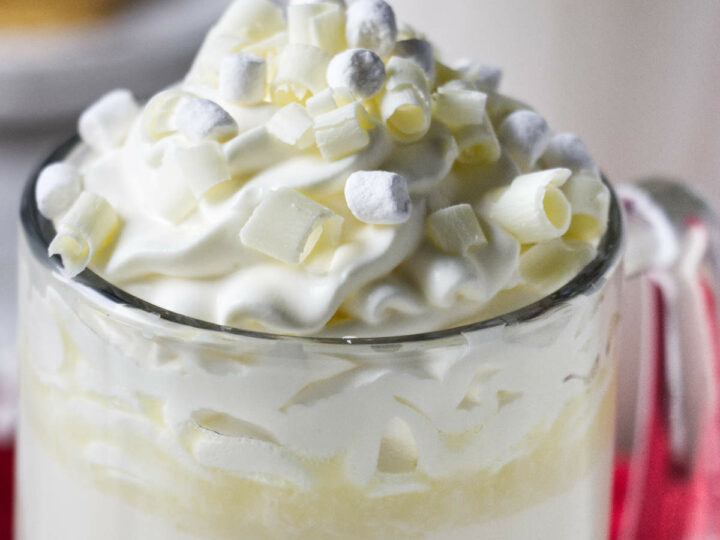 A mug of white hot chocolate with mini marshmallows and whipped cream on top.