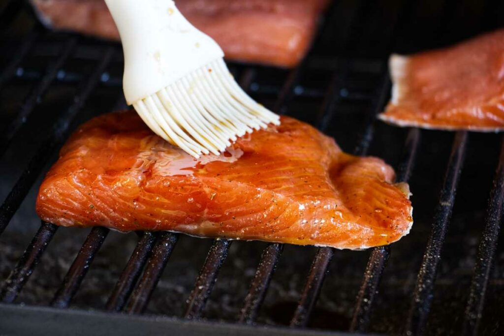 Brushing a glaze over the salmon while it is on the grill.