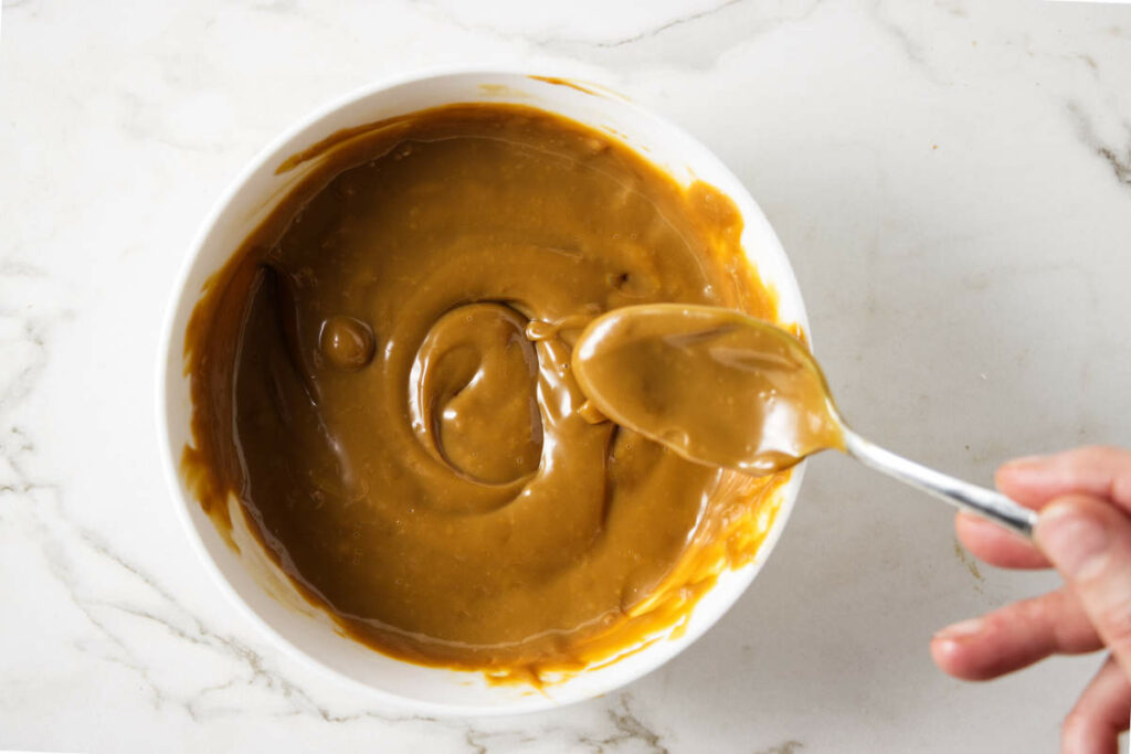 Stirring cream into a dish of dulce de leche.