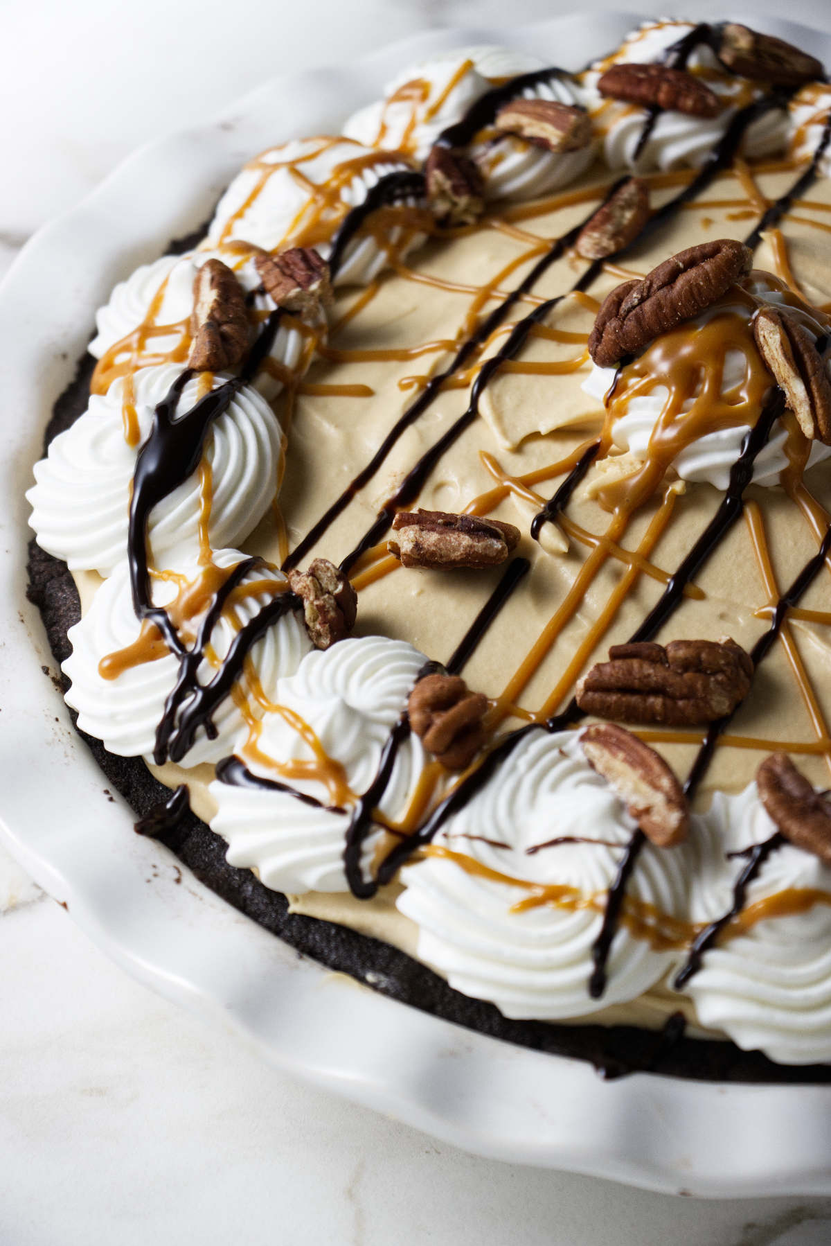 A caramel cream pie with pecans, chocolate sauce, and caramel sauce.