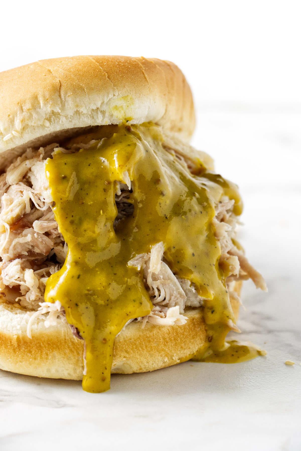 A shredded chicken sandwich with gold bbq sauce.