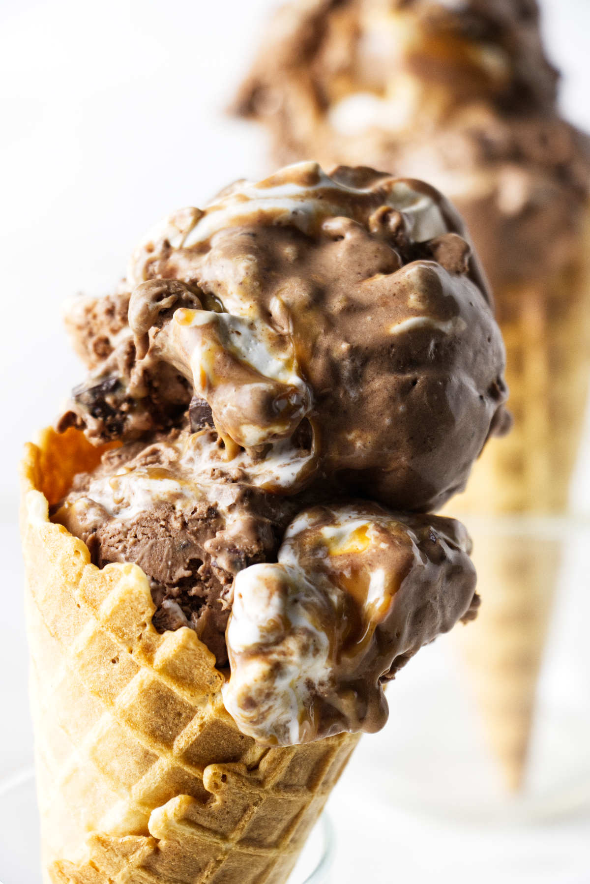 Two sugar cones topped with ice cream.