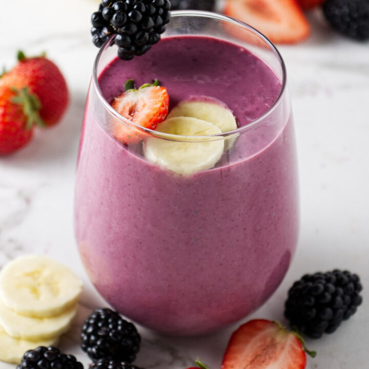 A blackberry strawberry banana smoothie in a short glass.