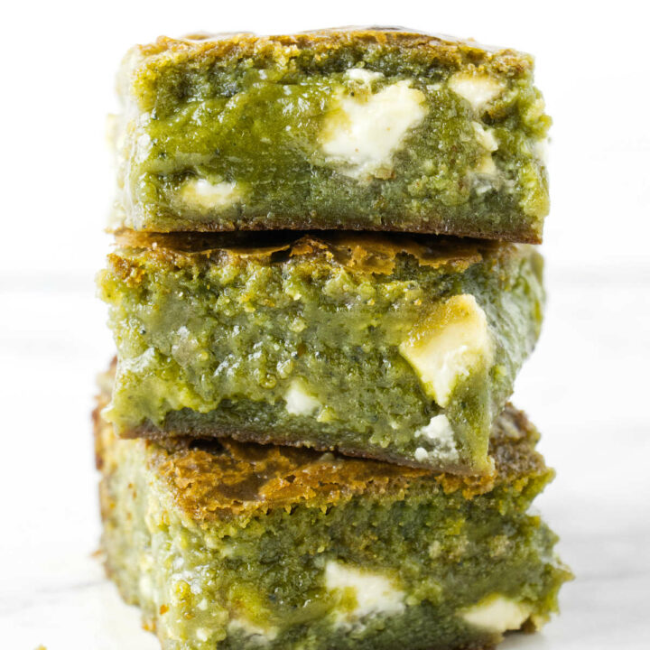 A stack of three matcha brownies with white chocolate chunks.