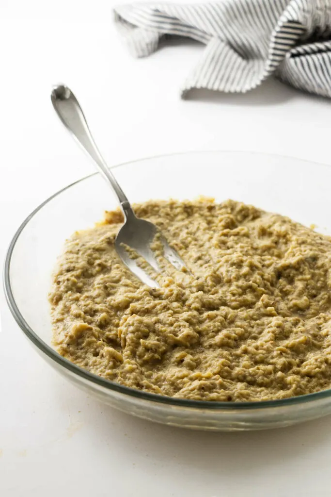 Mashing roasted eggplant with a fork.