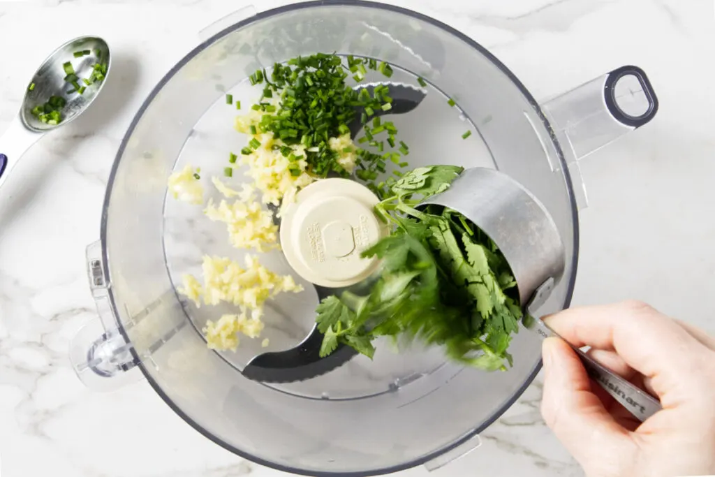 Adding herbs to a food processor.