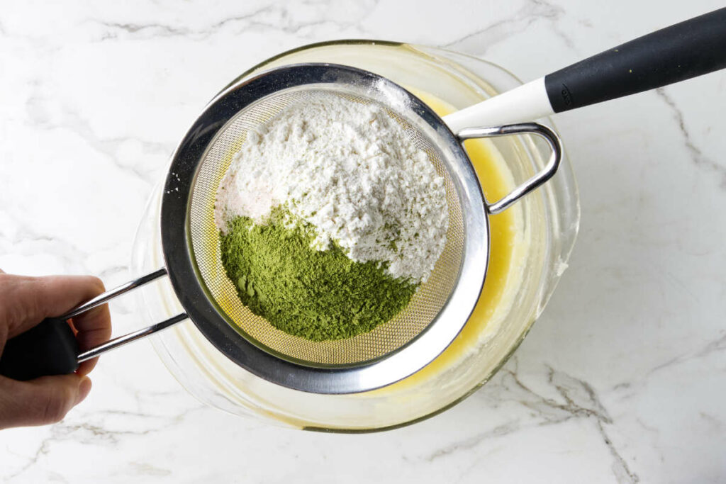 Sifting matcha powder, flour, and salt over the brownie batter.