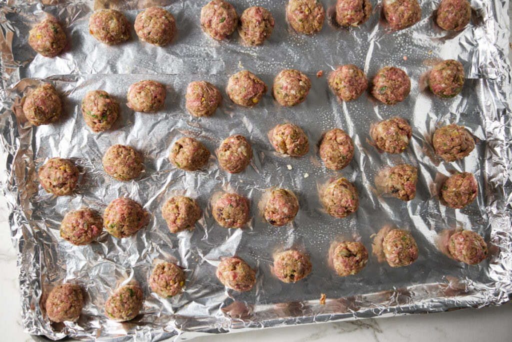 Raw lamb meatballs on a baking sheet.
