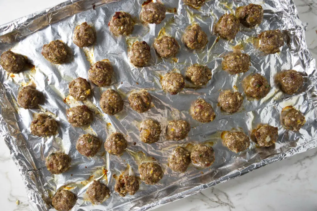 Baked meatballs on a sheet pan.