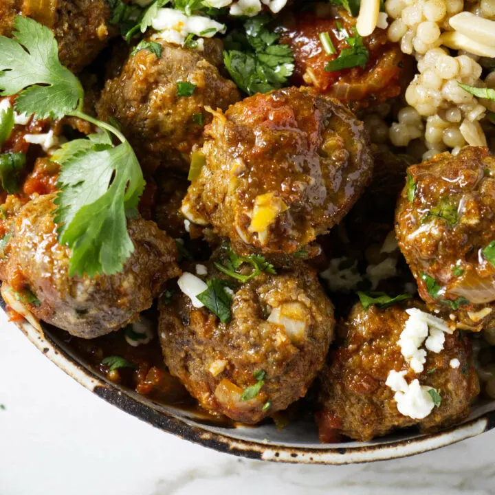 Moroccan lamb meatballs in a bowl with orzo and tomato sauce.