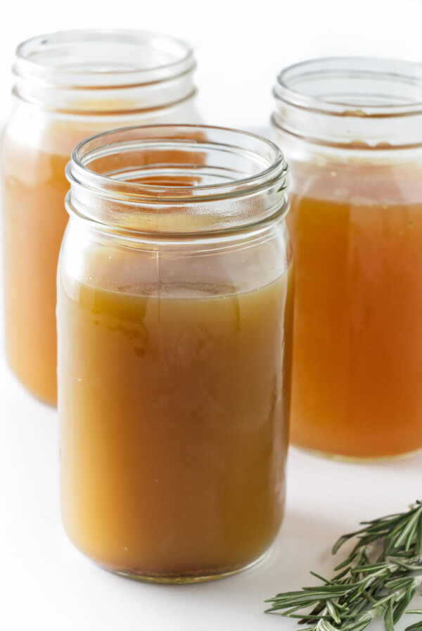 Glass jars filled with homemade chicken bone broth.