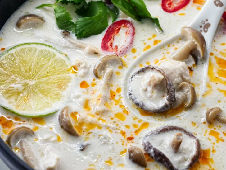 a bowl of Tom Kha Soup garnished with chili oil and fresh Thai basil.