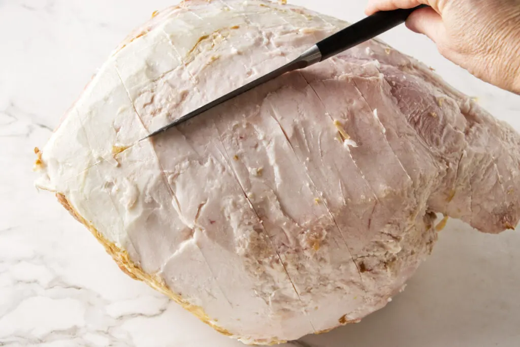 Scoring the fat layer on a ham.