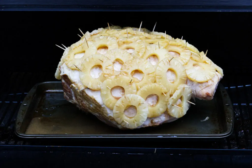 A ham covered in pineapple rings on the traeger grill.