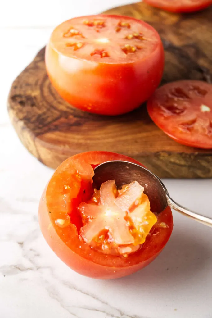 Scooping the center out of a tomato.