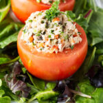 A tuna stuffed tomato on a bed of lettuce.