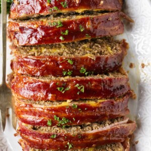 A bacon wrapped meatloaf on a serving platter.