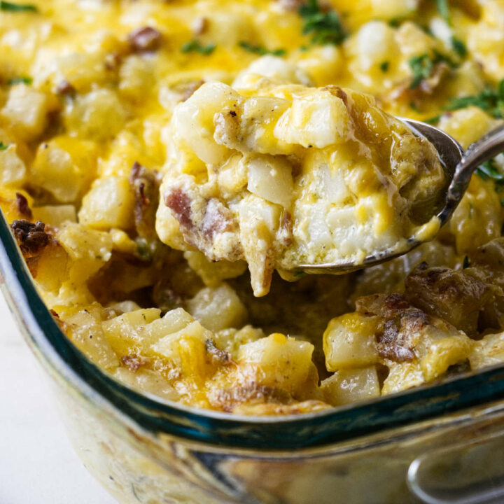 Scooping cheesy potatoes out of a casserole dish.
