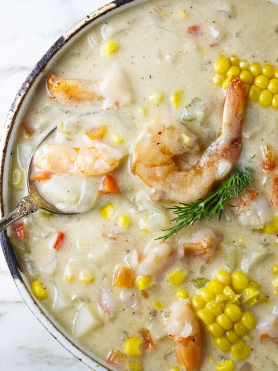A large bowl of chowder with shrimp and corn.