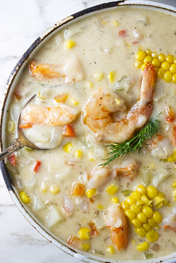 A large bowl of chowder with shrimp and corn.